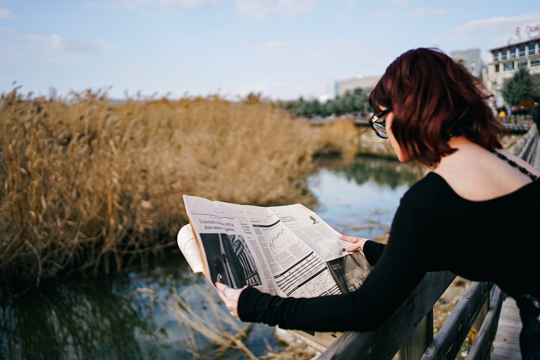 woman reading newspaper by serene lakeside